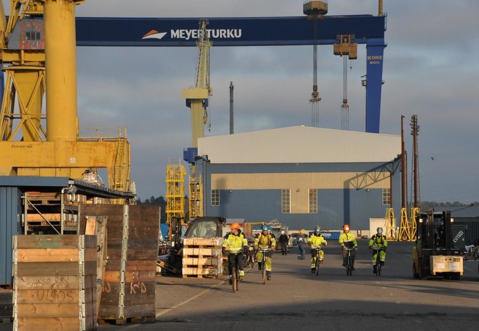 Varvsarbetare åker cykel på varvsområdet vid varvet Meyer Turku i Åbo