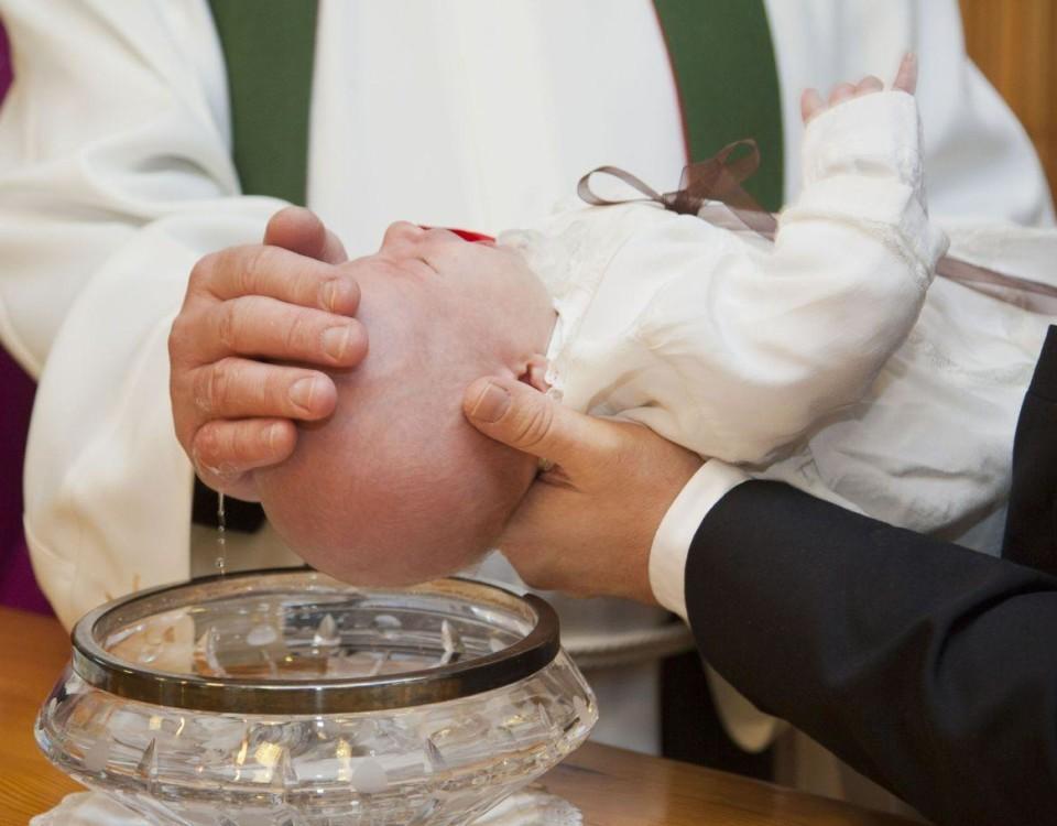 Ett barn döps i en kyrka.