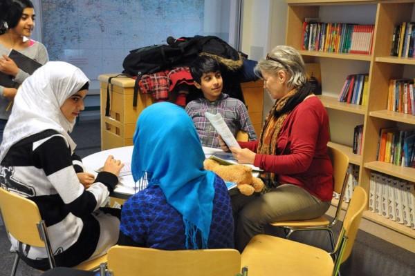 barn av utländsk härkomst och en kvinna i ett klassrum