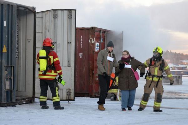 Brandmän leder folk ur rykande container