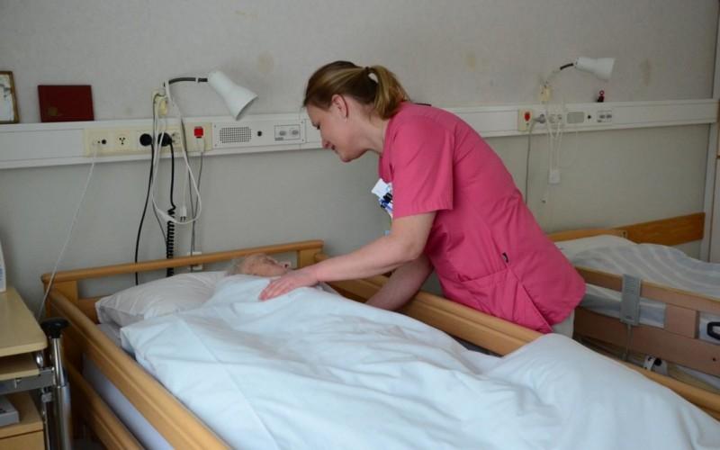 Sköterska böjer sig ner och talar med en patient
