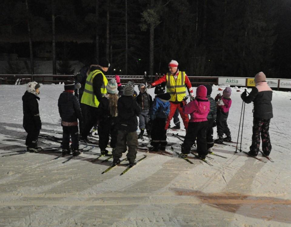 en grupp med barn och en ledare på skidor