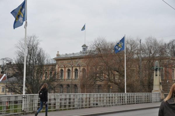 Stadshuset i Åbo med Aura bron och flaggstångar med stadens flagga hissade i förgrunden.