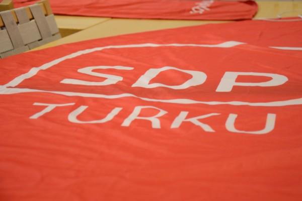 Röd skylt med texten "SDP Turku" ligger på ett bord.