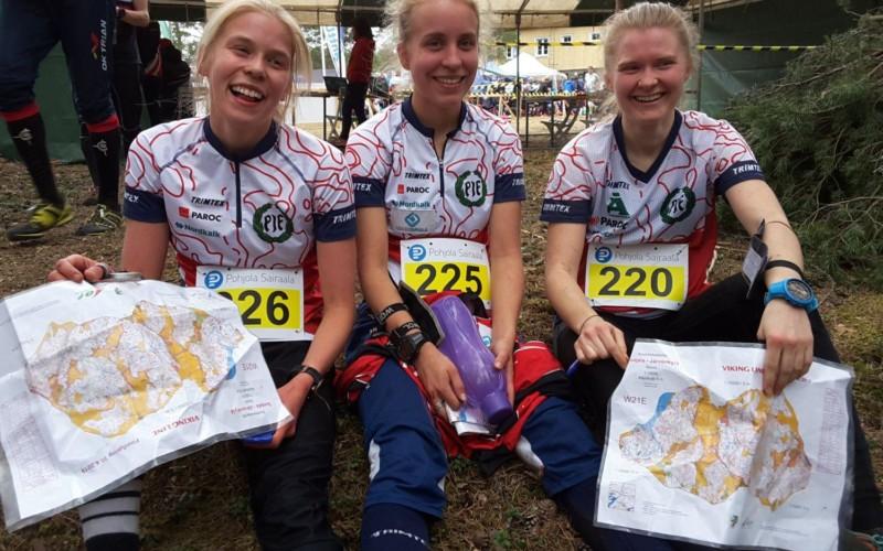Tre glada kvinnor i sportkläder, med kartor i händerna
