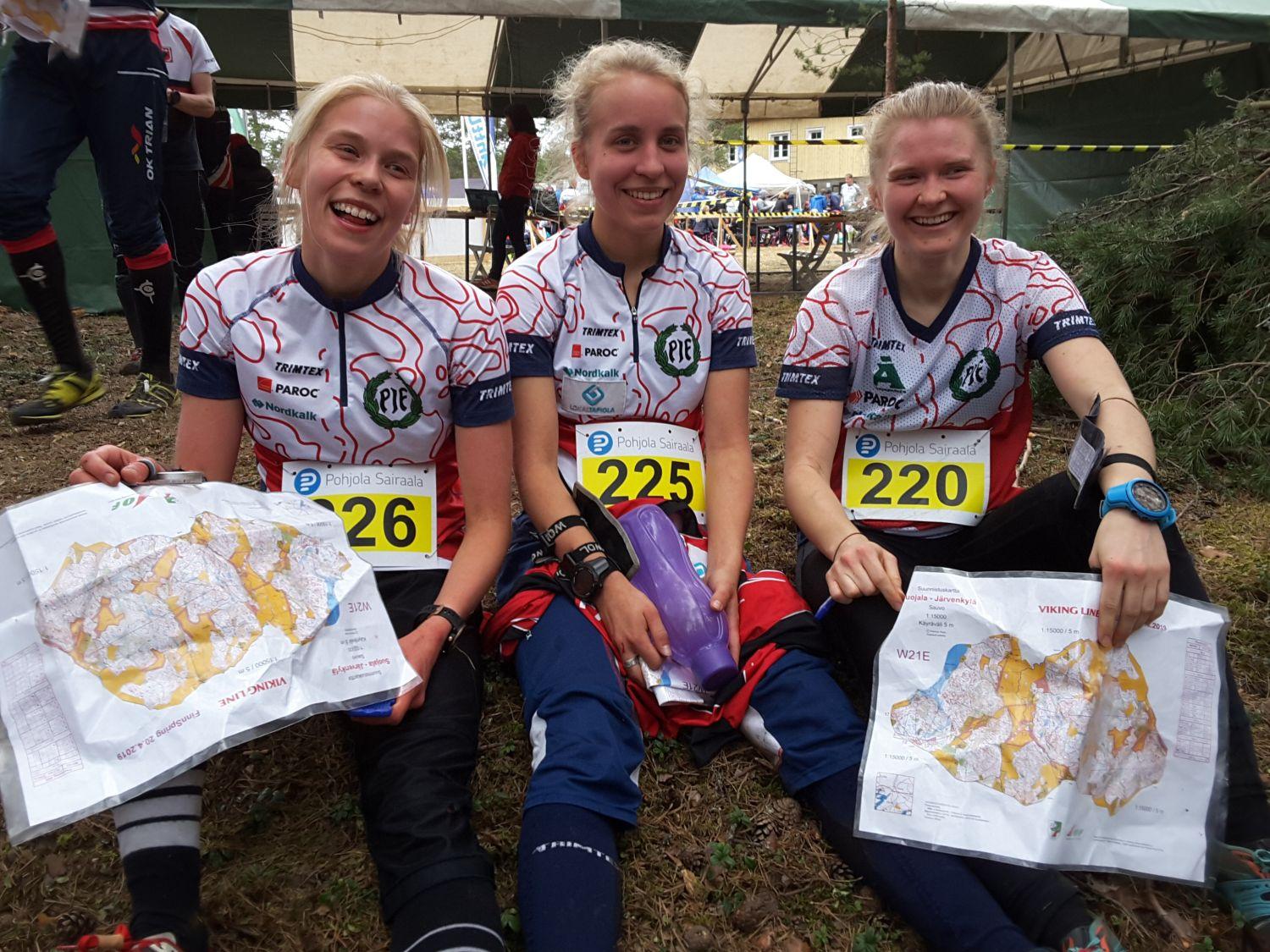 Tre glada kvinnor i sportkläder, med kartor i händerna