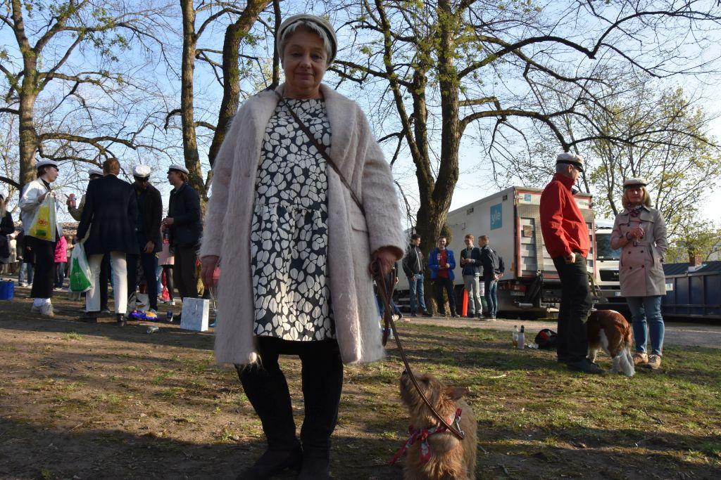 En kvinna står i en park med en liten brun hund av rasen norwichterrier