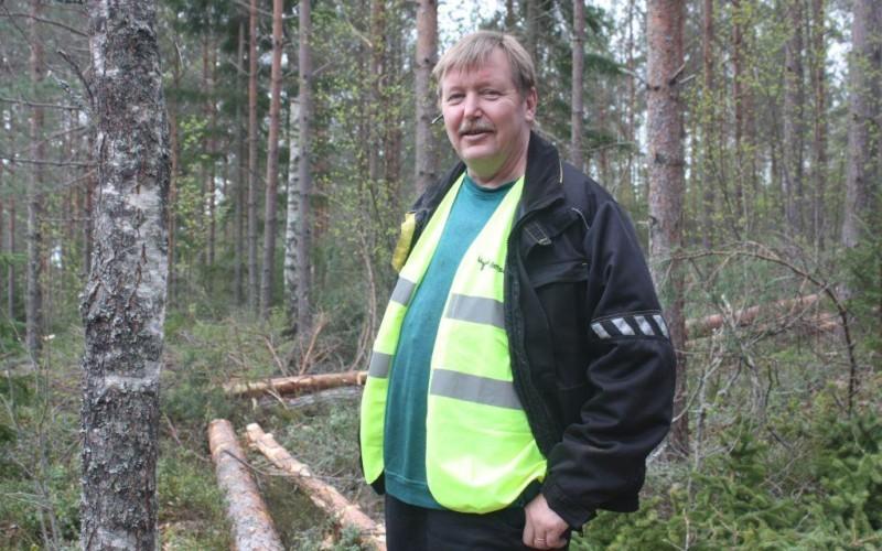 Halvbild på Kenneth Stenberg som ser in i kameran, skog i bakgrunden.