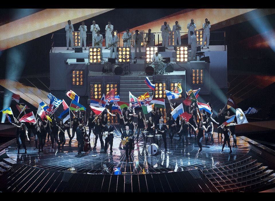 En stor scen fylld med folk som håller i olika länders flaggor.