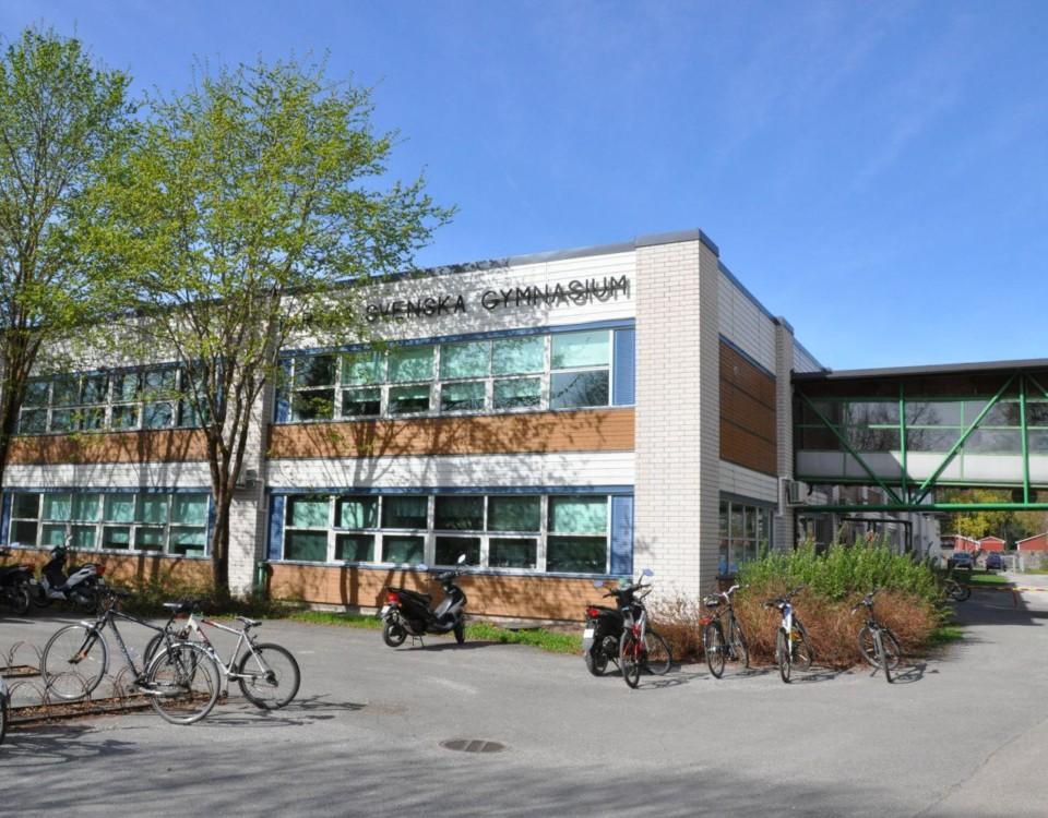 en skolbyggnad med cyklar och mopeder utanför