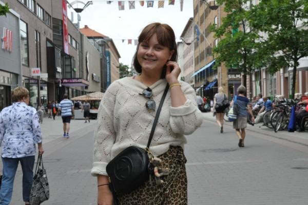 En leende kvinna står på gågatan i Åbo. I bakgrunden ser man ett myller av människor.