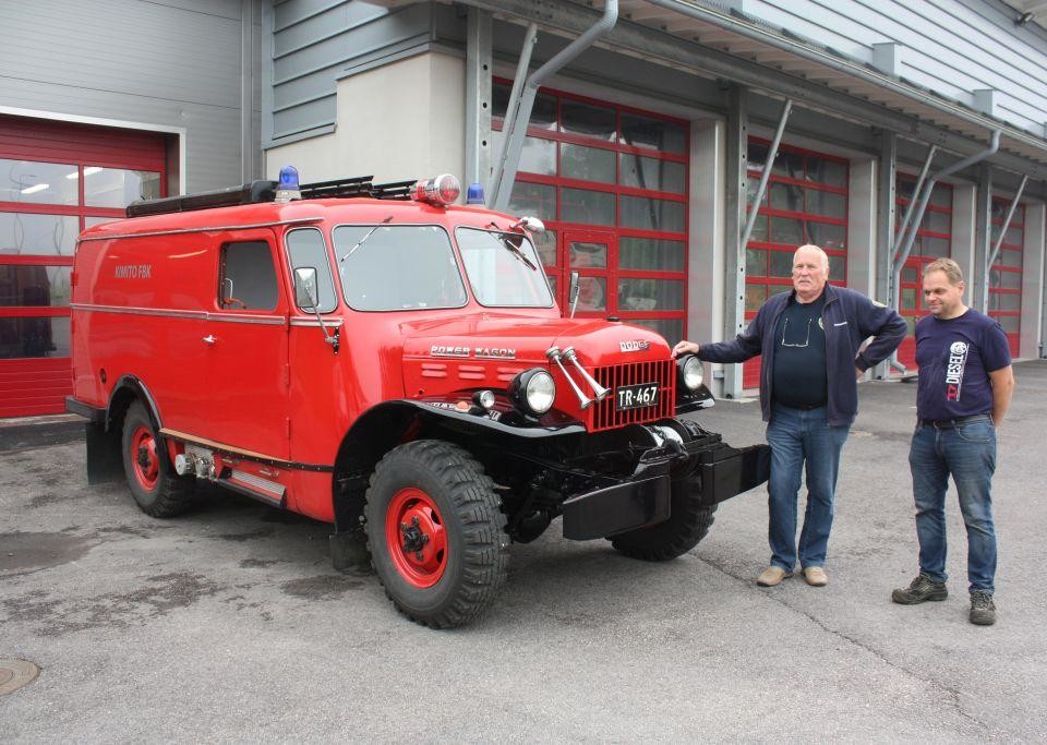 Röd brandbil från 1940-talet, bredvid står Per Sundström och Hasse Korsström, Kimito brandstation i bakgrunden
