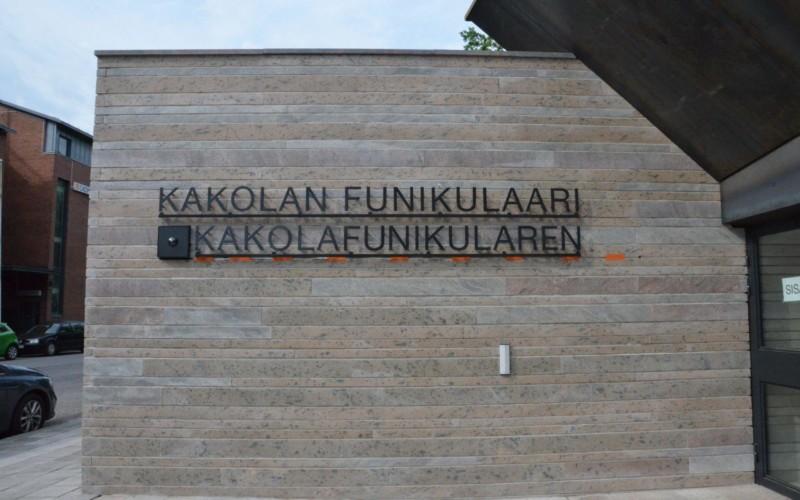 Texten Kakolanfunikulaari och Kakolafunikularen monterade på väggen vid ingången till snedhissen