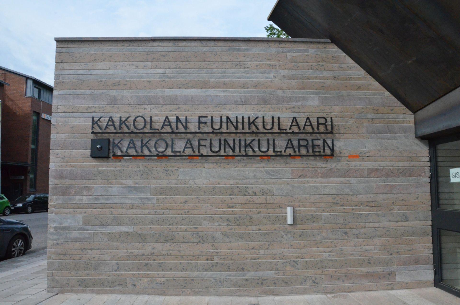 Texten Kakolanfunikulaari och Kakolafunikularen monterade på väggen vid ingången till snedhissen