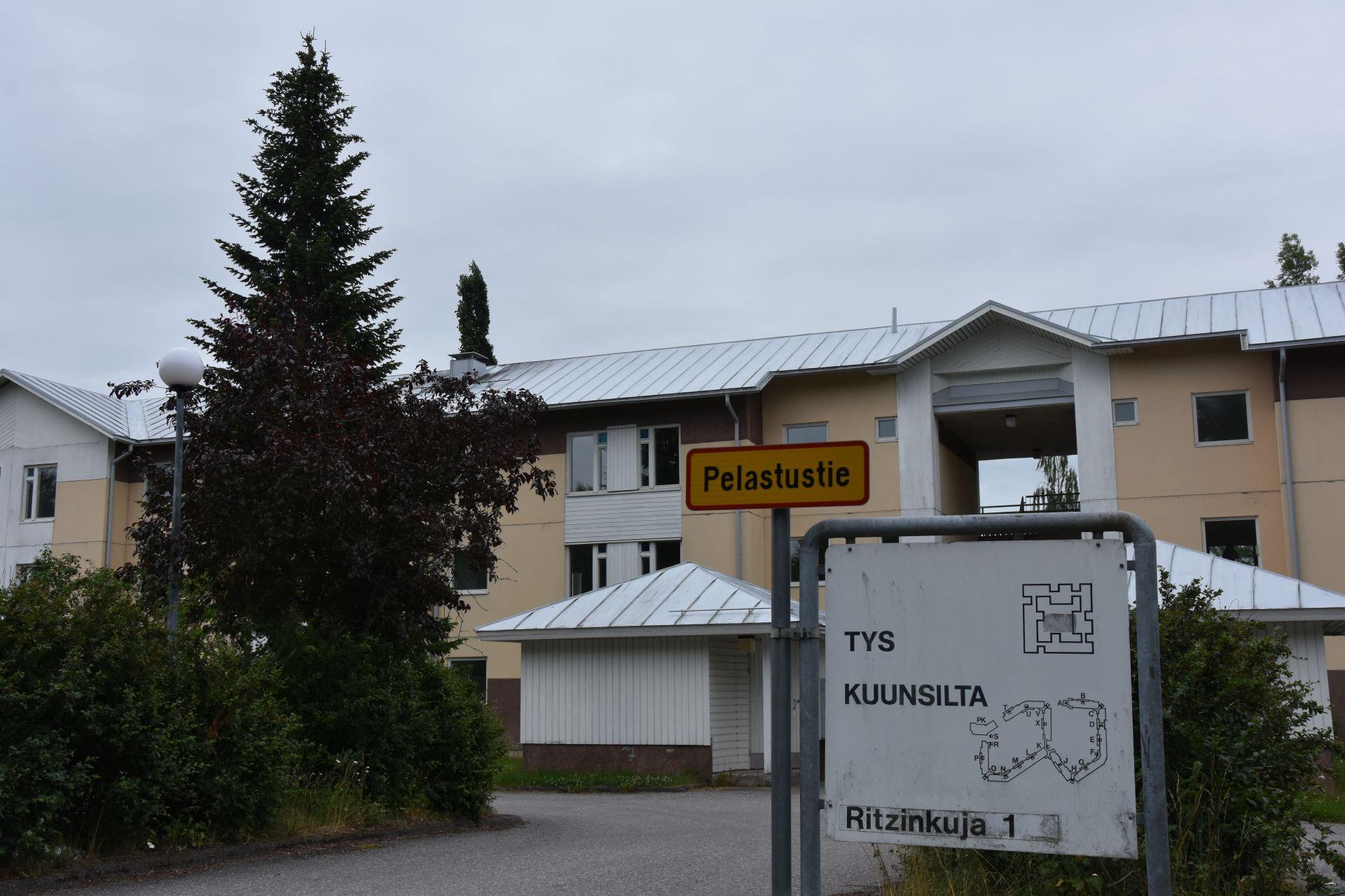 En skylt med en karta över Kuunsilta-bostadskomplexet och Studentbystiftelsens logotyp framför ett trevåningshus.