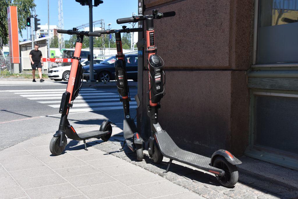 Tre elsparkcyklar står parkerade på trottoaren i ett gathörn