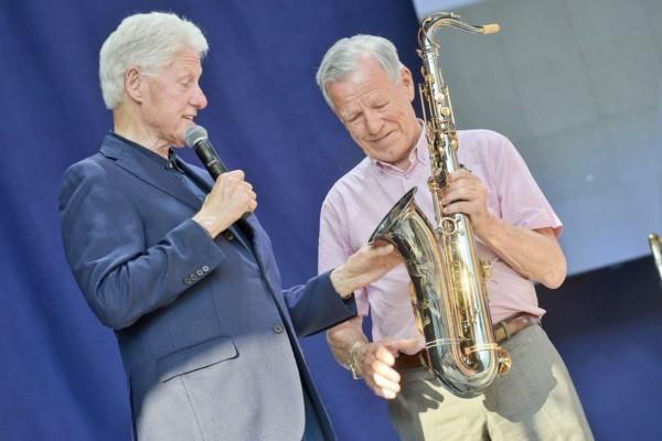 Bill Clinton och Anders Wiklöf står på en scen. Wiklöf överräcker en saxofon till Clinton.