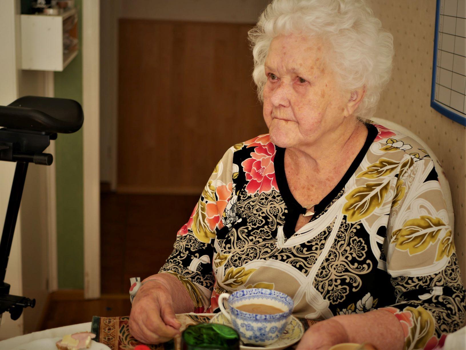Äldre kvinna dricker kaffe