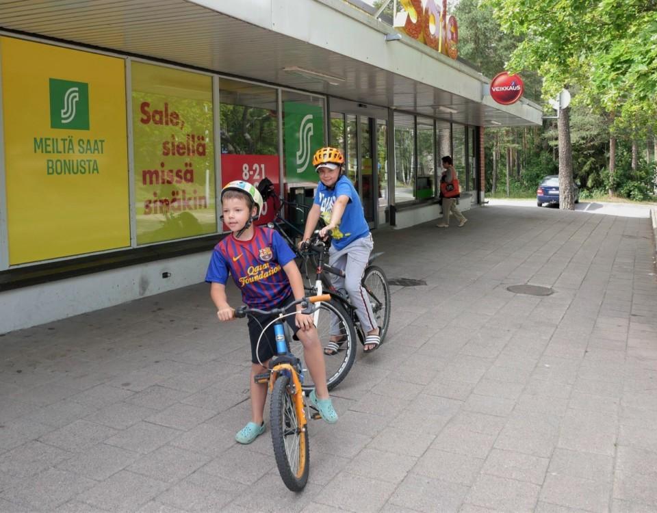 Två pojkar står på sin cykel utanför matbutik