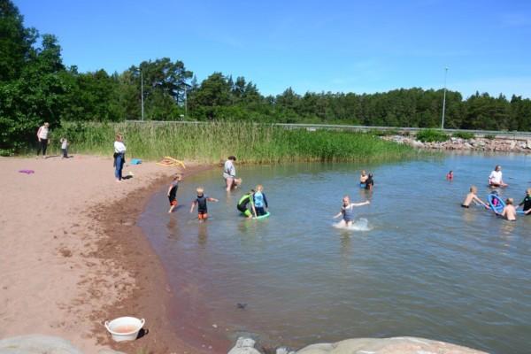Ett tiotal barn plaskar runt i vattnet vid Kannvik badstrand.