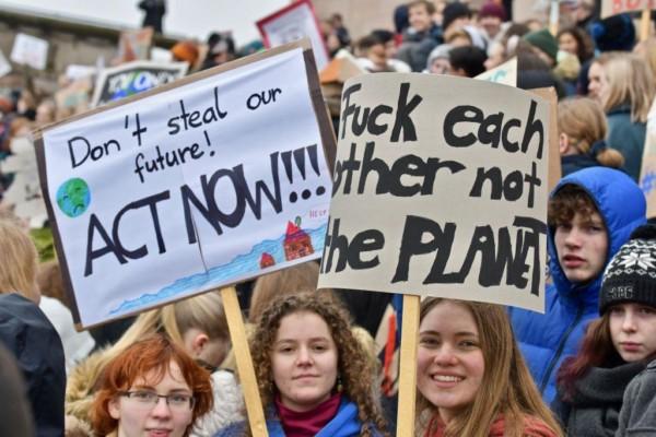 en grupp demonstranter och två skyltar med texterna "Don´t steal our future, act now" och "Fuck each other not the planet".