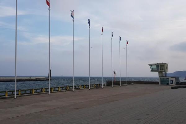 flaggstänger på kaj mot hav