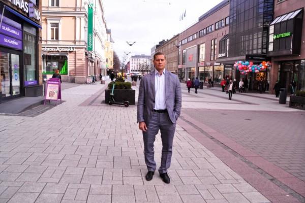 En man i grå kostym står på gågatan i Åbo.