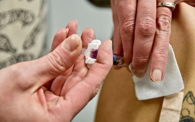 En vaccinspruta sticks i överarmen på en person.