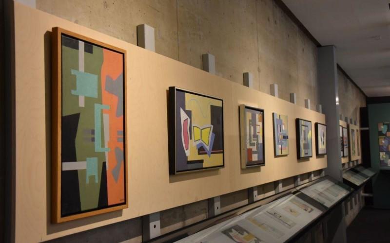 Färggranna och geometriska abstrakta målningar upphängda på en vägg.