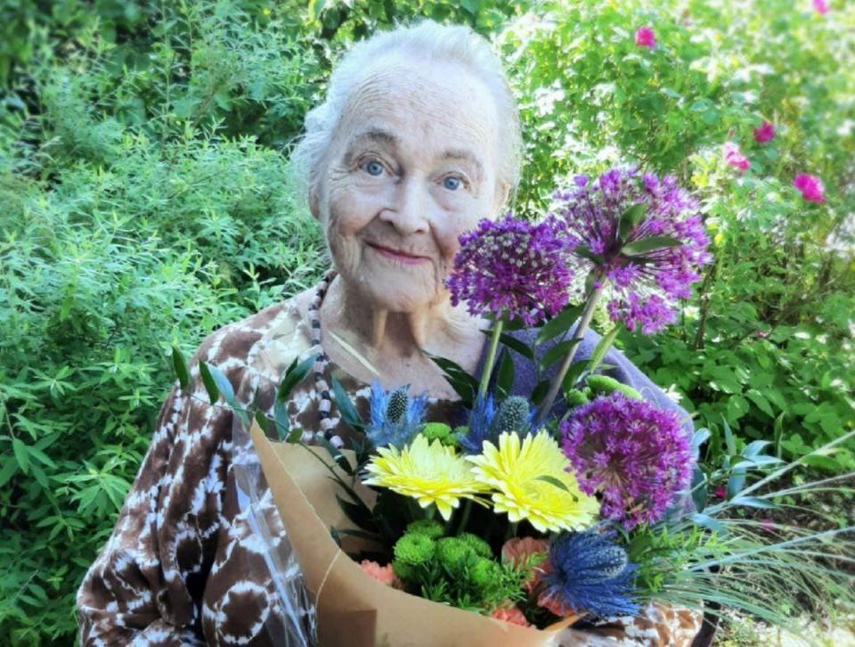 Porträtt av en äldre kvinna med en bukett blommor i famnen