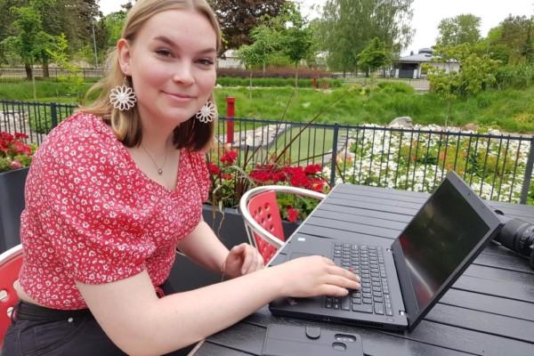 flicka sitter vid terrassbord med sin dator och mobil