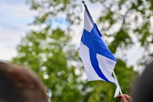 En hand som viftar med en finlandsflagga.
