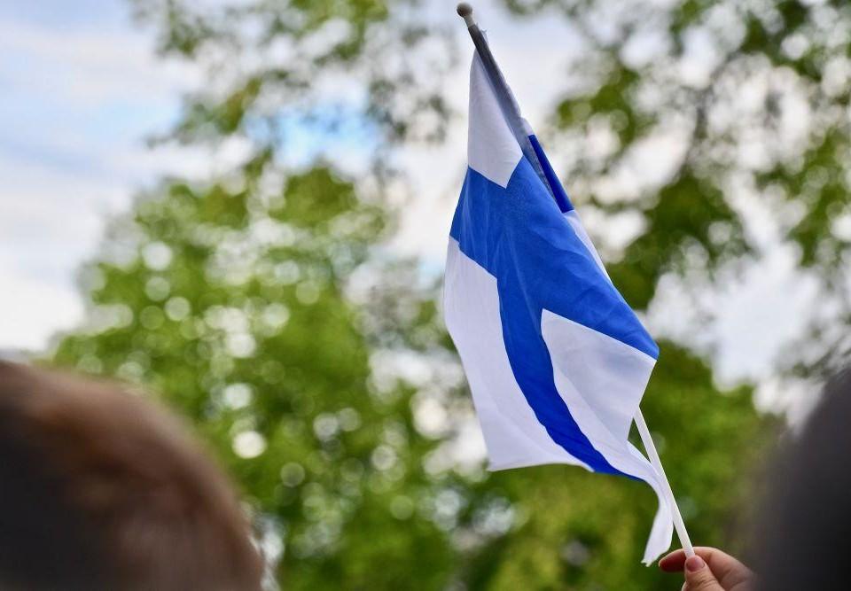 En hand som viftar med en finlandsflagga.