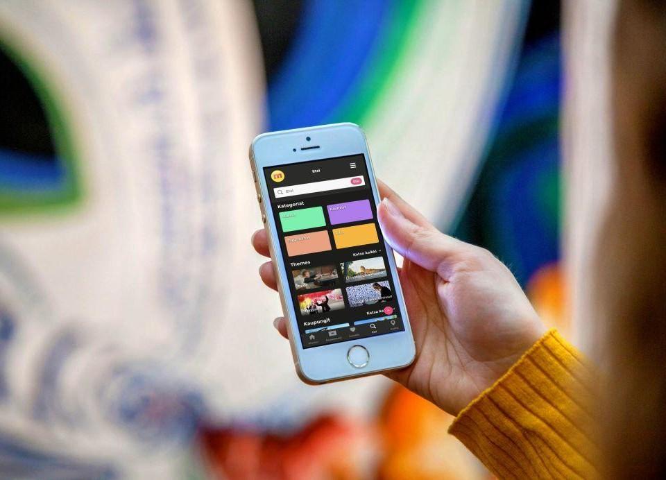En hand håller i en smarttelefon med en färgglad app öppen på skärmen.