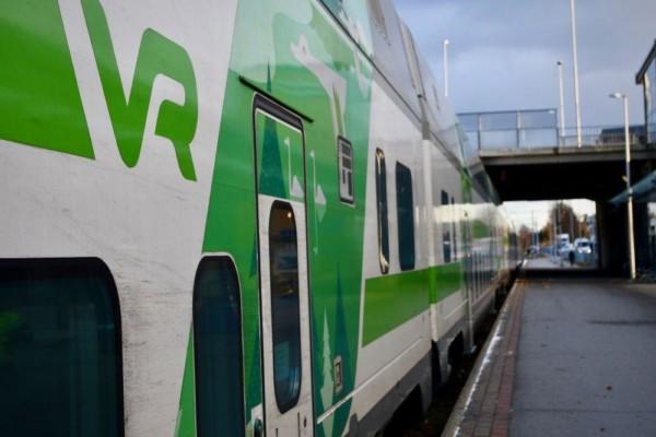 Sidan av ett vitt tåg med gröna dekorationen och texten "VR" skriven i grönt på sidan.