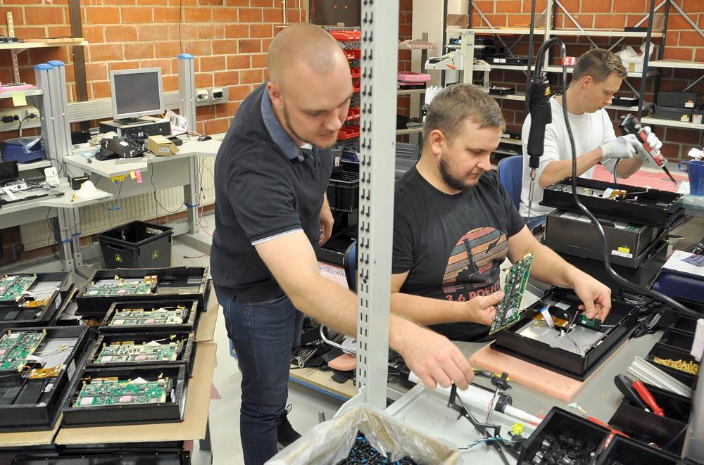 tre män monterar elektronikkomponenter