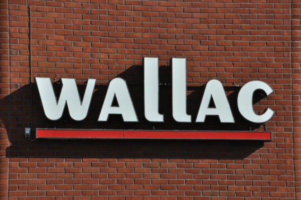 En logga med texten Wallac på en tegelvägg.