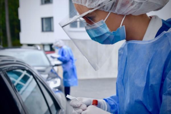 Skötare i skyddsmundering utför test på personer i bilar.