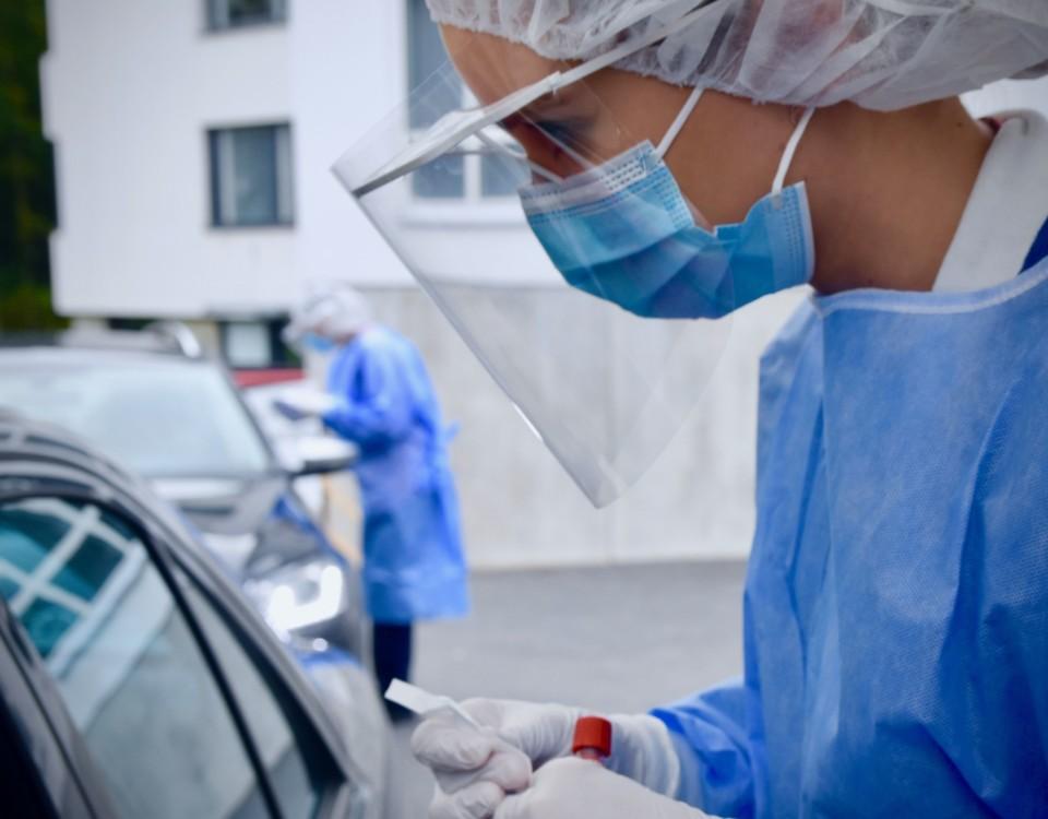 Skötare i skyddsmundering utför test på personer i bilar.