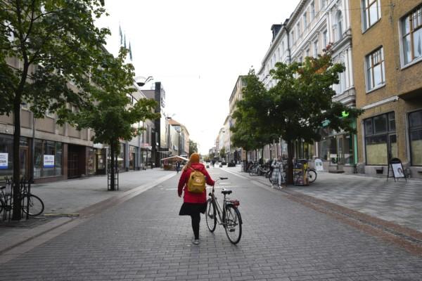 människa leder cykel på rätt tom o öde gata