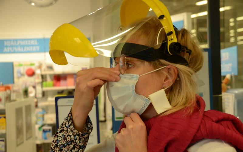 Kvinna trycker åt munskydd vid näsan.