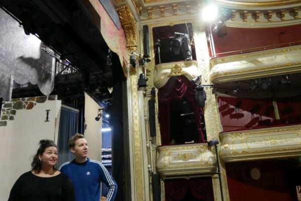 en man och en kvinna står på en teaterscen och blickar ut över en tom salong