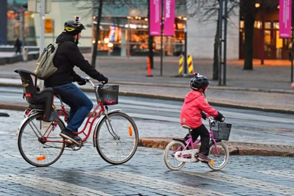 Far och dotter cyklar i trafik