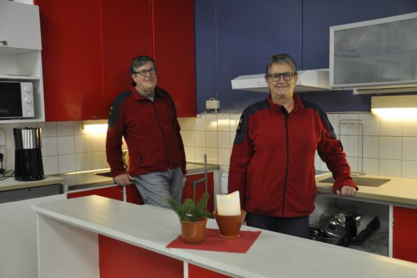 Två personer i ett nyrenoverat kök i färgerna blått, vitt och rött.