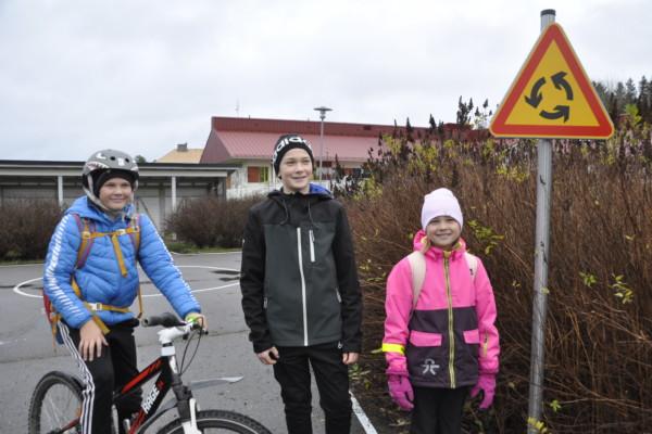 Tre barn vid ett minitrafikmärke som varnar om rondell