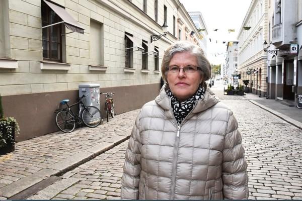 Katri Viinikka i grå jacka på en kullerstensgata i Helsingfors.