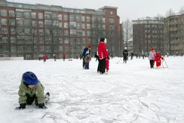 Barn åker skridsko på isbana i höghuskvarter
