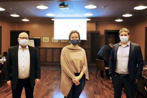 Tre personer med munskydd i mötessal
