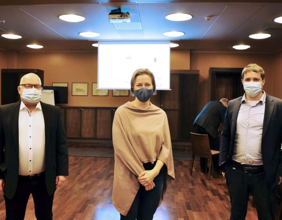 Tre personer med munskydd i mötessal