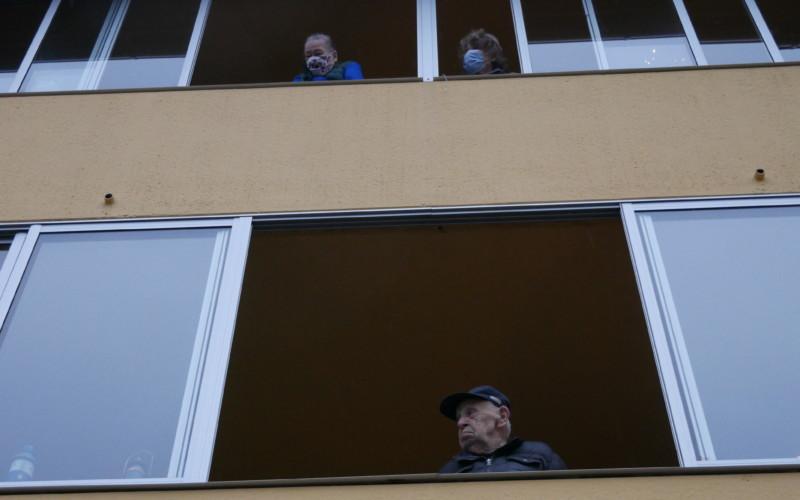 några personer tittar ut från sina balkonger